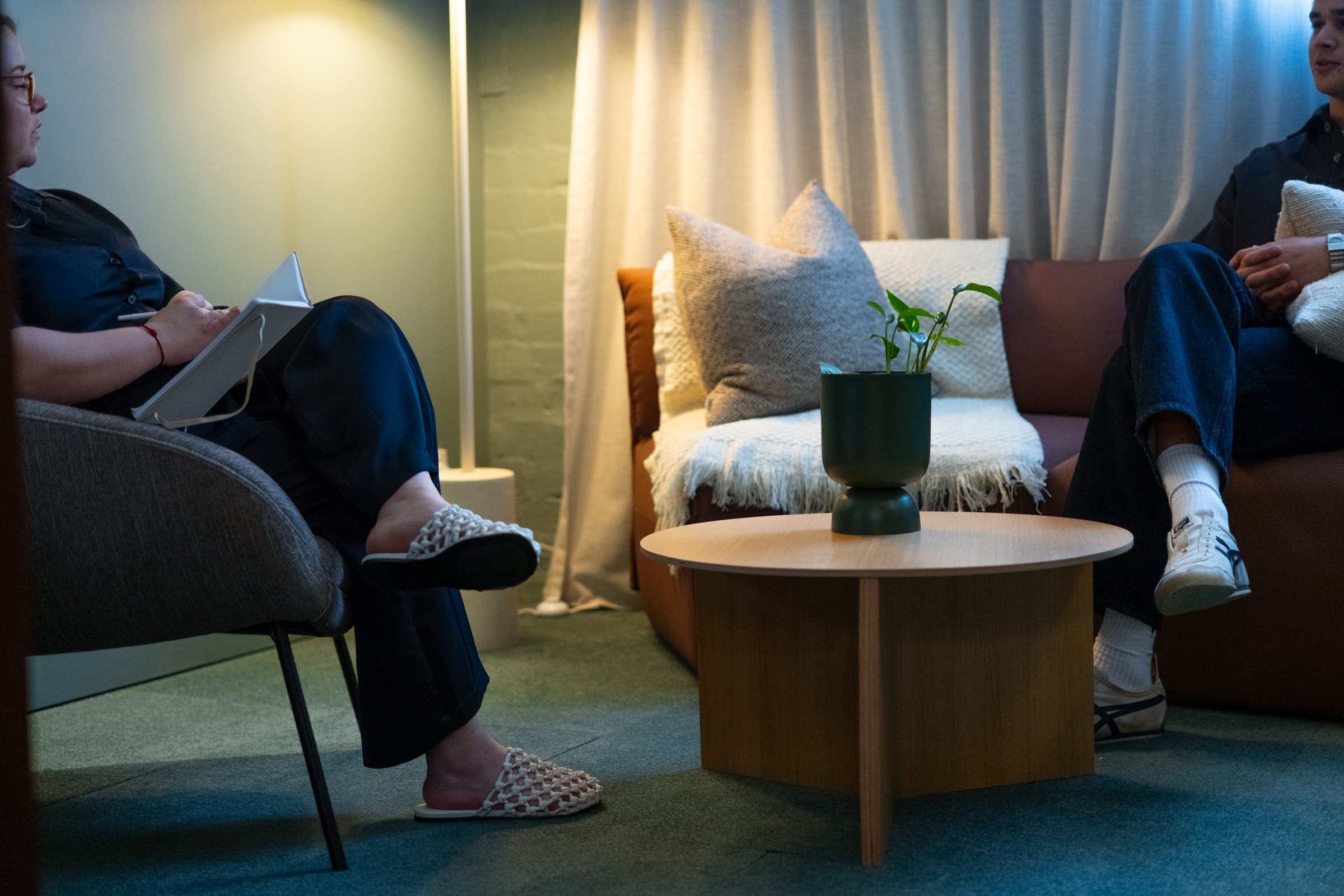 A psychologist taking notes during a session with a client in a warm therapy room