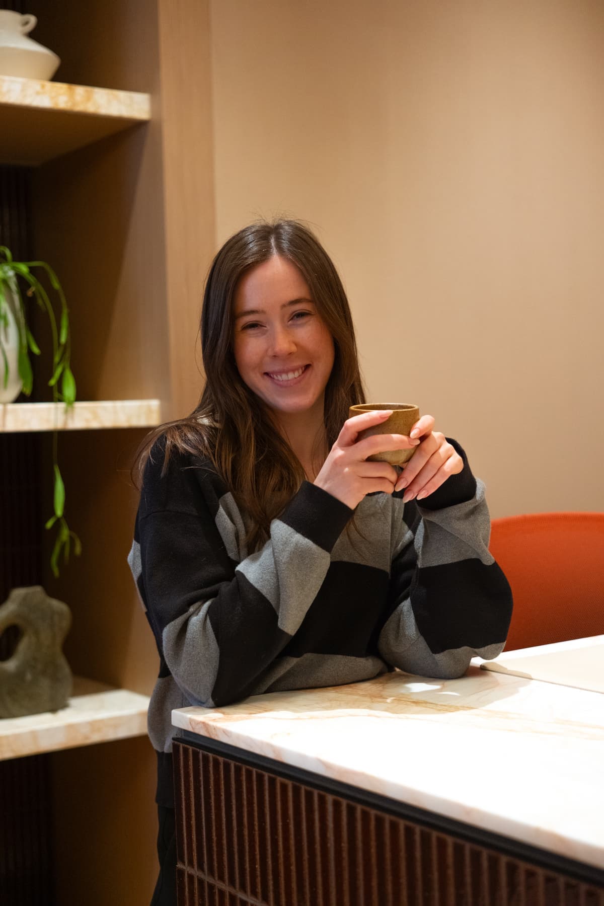 A woman smiling over a cup of tea at a warm reception counter
